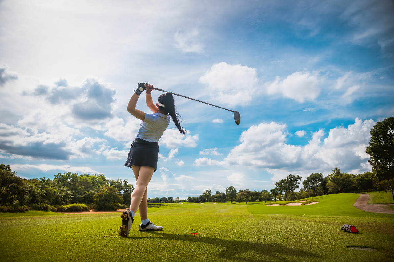 Golfer teeing off at Bali National Golf Club with ocean view background